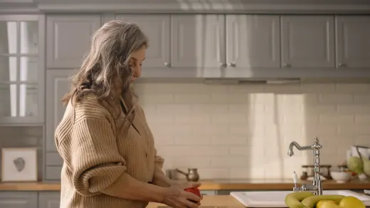 A senior dog eating from a stainless steel bowl in a home kitchen